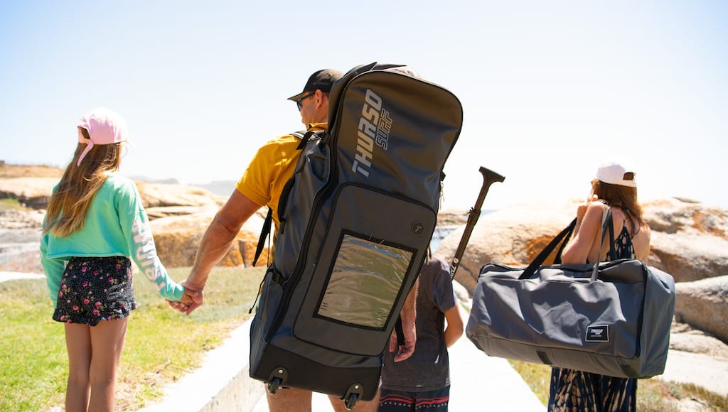 Family carrying their paddleboards down to the shoreline