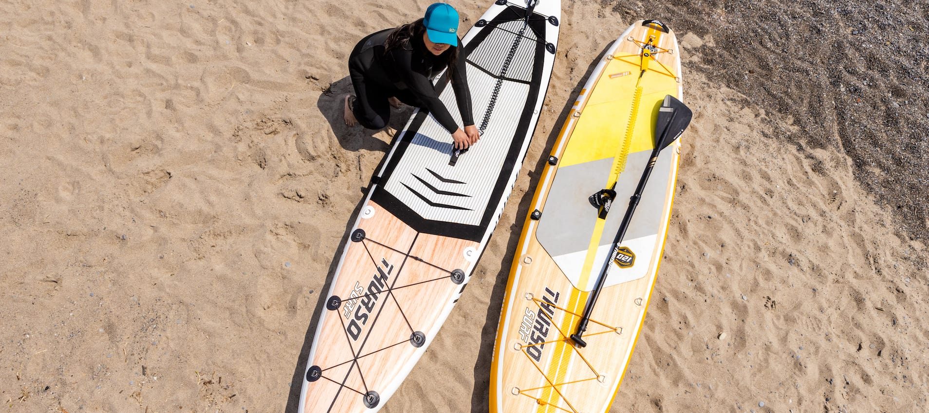 Woman leaning over two Thurso Surf inflatable stand up paddleboards
