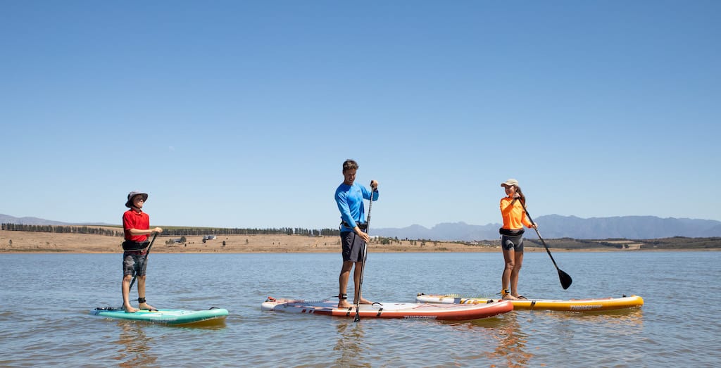 SUP instructor in the water with two students standing on their boards