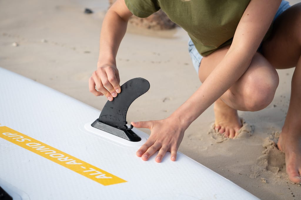 Person installing a SUP fin on a Thurso Surf Waterwalker SUP board